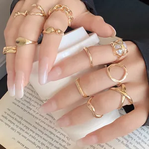 Macro view of trendy gold irregular geometric open ring set worn on hand with white cup