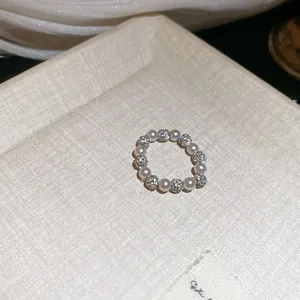 Macro dettaglio che mostra le eleganti perle e le sfere di cristalli pavé di questo anello