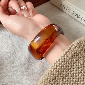 Vista dettagliata di un ampio bracciale in resina ambrata con motivi irregolari