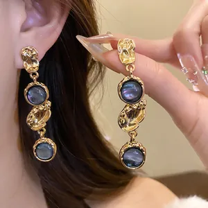 Detailed view of vintage palace style gold-tone earrings featuring dark iridescent resin