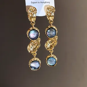 Detail showing vintage palace style gold drop earrings with blue iridescent resin insets