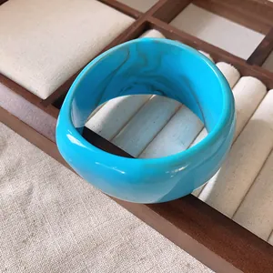 Dettaglio di un ampio bracciale in resina marmorizzata turchese su vassoio per gioielli