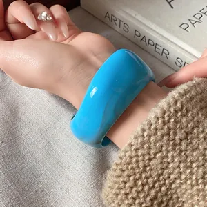 Vista dettagliata di un ampio bracciale blu lucido irregolare sul polso di una modella