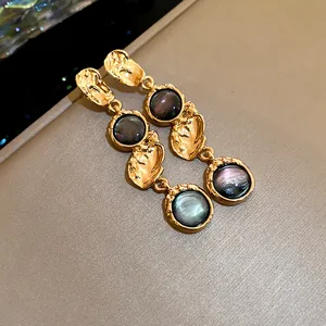 Close-up of vintage gold-tone drop earrings with iridescent dark pearlescent resin inserts