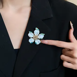 Detailed view of elegant white enamel flower brooch with crystals pinned on a black blazer