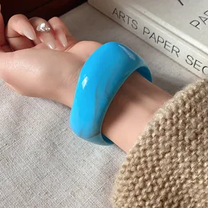 Primo piano di un ampio bracciale rigido azzurro irregolare con effetto marmo al polso
