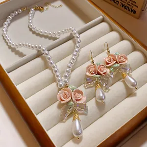 Detail eines Vintage-Perlenschmucksets mit rosa Keramikrosen und Tropfenperlen.