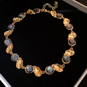 Detail of a vintage gold-plated necklace with round iridescent resin inserts in a jewelry box.