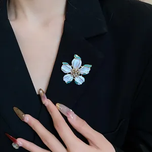Detail view of an elegant white enamel flower brooch pinned on a classic black blazer jacket.