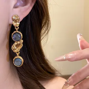 Detailed close-up of vintage gold-toned resin round dangle earrings worn by a model