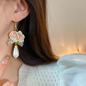 Detailaufnahme von Vintage-Keramikrosen-Ohrringen mit Perlen und schillernder Schleife