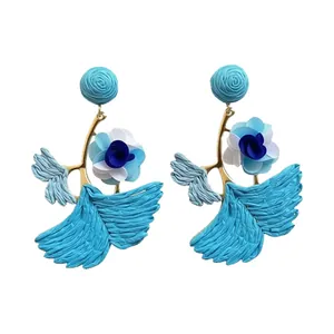 Blue and white raffia flower pendant earrings featuring a beach vacation aesthetic