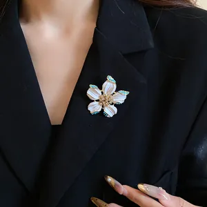 Detailed shot of a vintage white enamel flower brooch with crystal and pearl accents
