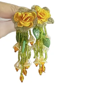 Vibrant yellow fabric rose earrings with green beaded tassels for a bohemian vacation look.