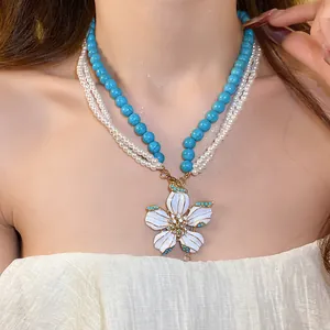 Detailed view of a vintage flower pendant necklace with turquoise beads and pearls