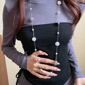 Elegant long fashion necklace with silver metallic nuggets and round pearls shown on model