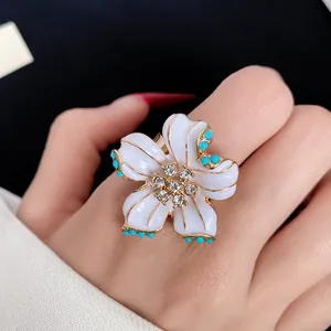 Close-up of elegant white enamel flower ring with sparkling crystal details