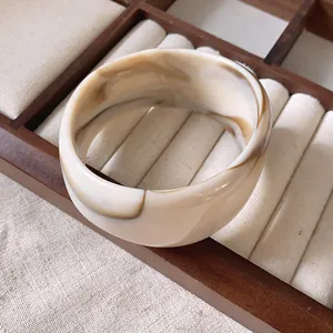Vista dettagliata di un elegante bracciale in resina marmorizzata su un vassoio di legno
