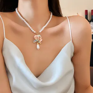 Elegante Perlenkette mit rosa Keramikrosen-Anhänger, getragen von einem weiblichen Model