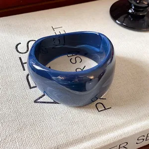 Vista dettagliata di un bracciale rigido largo in resina blu navy irregolare lucido