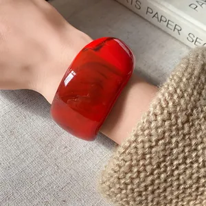 Vista dettagliata dell'ampio bracciale in resina rossa vibrante indossato sul polso