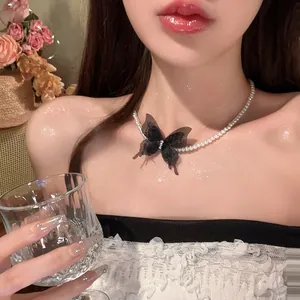 Detailed shot of a pearl choker necklace featuring a black mesh butterfly pendant on a model