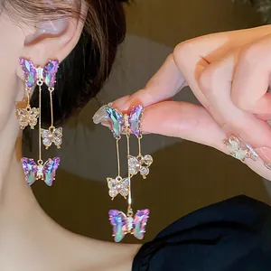 Gros plan de boucles d'oreilles à pampilles papillon irisées étincelantes de style long