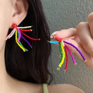Nahaufnahme von handgefertigten bunten Regenbogen-Perlenohrringen an Model und Hand