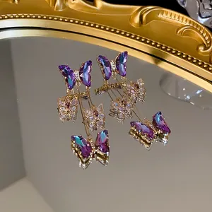 Détail de boucles d'oreilles papillon à pompon violet avec zirconiums