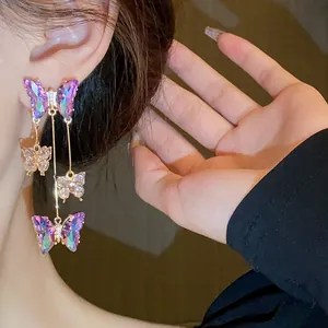 Vue détaillée d'élégantes boucles d'oreilles papillon en zircon violet portées par un mannequin