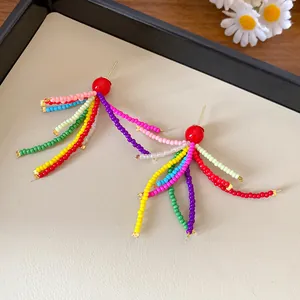 Detailaufnahme von handgefertigten bunten Perlen-Quasten-Ohrringen mit roter Harzperle.