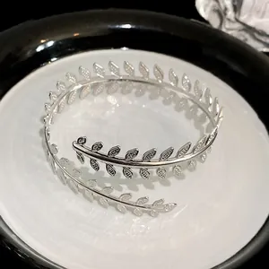 Dettaglio di un elegante bracciale a polsino a foglia d'argento su un piatto bianco