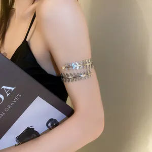 Dettaglio di un bracciale da braccio elegante a foglia d'argento su una modella.