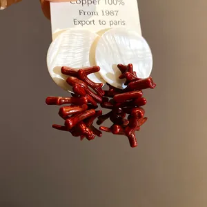 Detailansicht der roten Korallenharz- und weißen Muschelscheiben-Ohrstecker im Retro-Stil