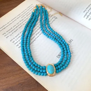 Detailed view of triple-layer turquoise beaded necklace on vintage book pages