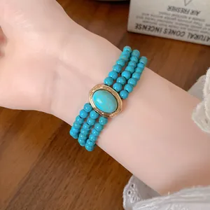 Detail shot of a multi-layer turquoise beaded bracelet with gold vintage centerpiece