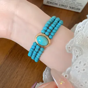 Macro view of vintage triple-strand turquoise beaded bracelet with gold oval centerpiece