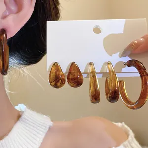 Detail view of amber resin waterdrop studs and hoop earrings set on white display card