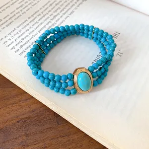 Close-up of a multi-strand turquoise beaded necklace displayed on a vintage book
