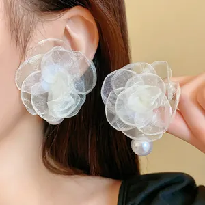 Close-up macro detail of elegant white mesh gauze flower stud earrings with pearl drop.