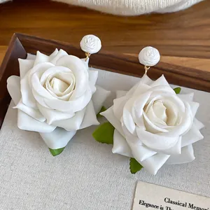 Dettaglio di orecchini a lobo a forma di rosa in tessuto bianco con petali delicati