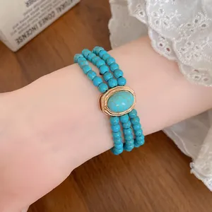 Close-up detail of multi-layer turquoise beaded necklace with gold tone centerpiece.