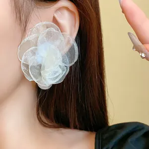 Detail shot of elegant mesh flower earring with a pearl center on an ear.