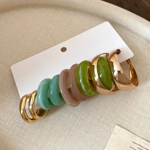 Detailed view of colorful resin and gold hoop earrings set on a white display card