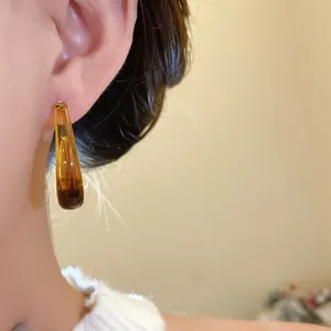 Macro detail view of a vintage style amber resin teardrop earring worn by an elegant model