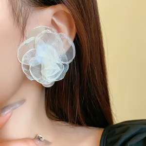 Close-up of elegant white mesh flower stud earrings with pearl centers on model's ear