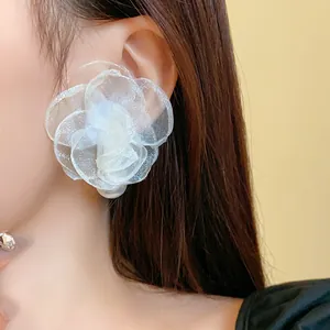 Detailed view of elegant white mesh flower stud earrings with pearls worn by model