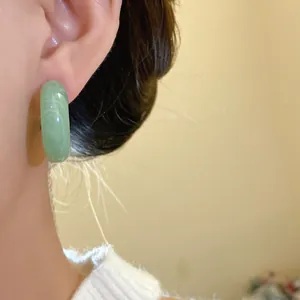 Close-up view of a vintage-style light green resin hoop earring worn on an ear for a soft look.