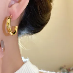Close-up of elegant chunky gold hoop earrings worn on ear with minimalist retro style
