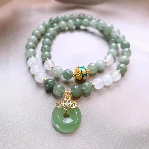 Macro detail of a Chinese style double-strand jade bead bracelet with golden charm.